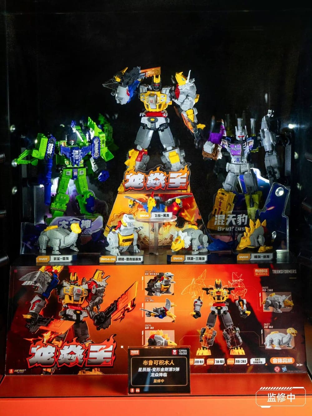 Etalase Blokees Transformers Defender Version 09 di CTE 2026: Volcanicus di tengah, diapit Devastator dan Bruticus, dengan lima Dinobot di depan.