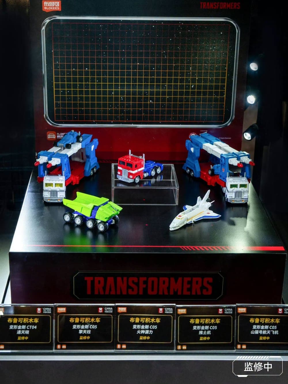 Etalase Blokees Wheels Transformers di China Toy Expo 2026: dua CT04 Ultra Magnus, Optimus Prime, kendaraan hijau, dan pesawat ulang-alik dari seri C05.